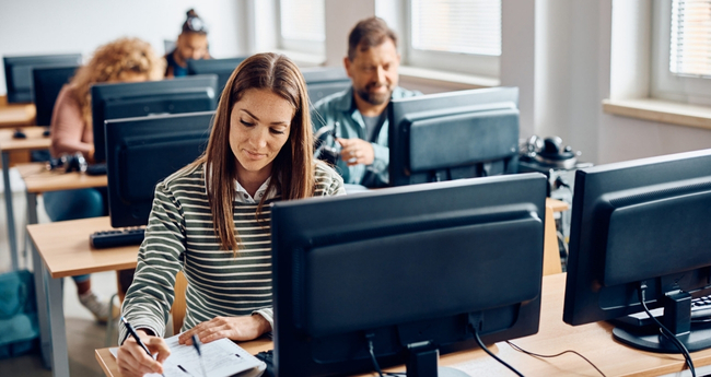 Professionals attending an IT training session with desktop computers in a classroom setting