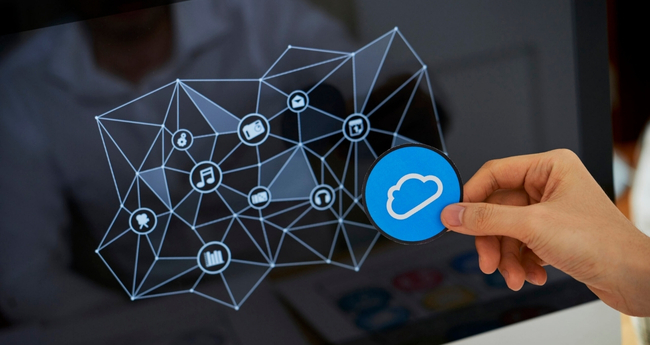 Hand placing a cloud icon in front of a digital network interface on monitor
