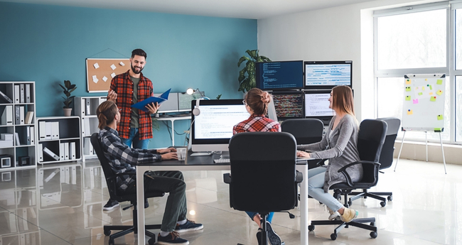 Tech team gathered around a table, engaging in planning and discussion in a modern workspace