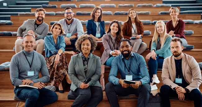 Large group of IT professionals smiling during a workshop or training session in an auditorium