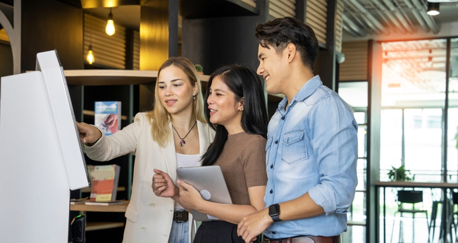 A team of young professionals using an interactive screen at a technology center