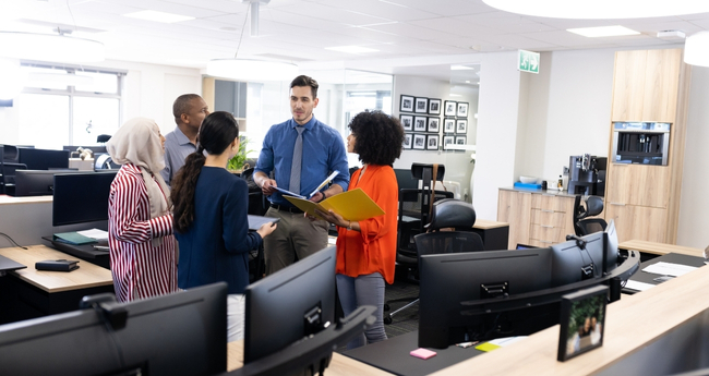 Group of diverse IT professionals discussing project in a modern office environment