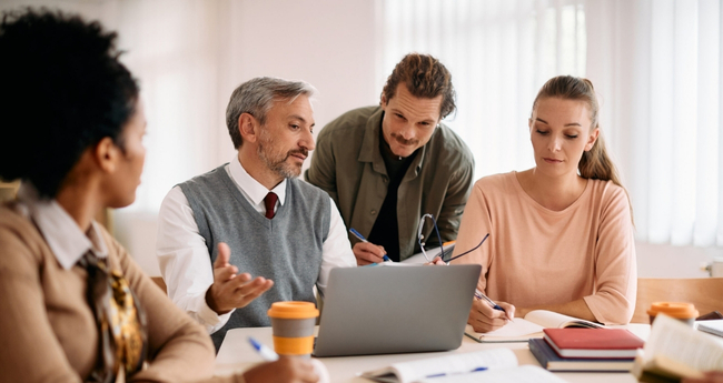 Mixed-age team discussing strategy around a laptop