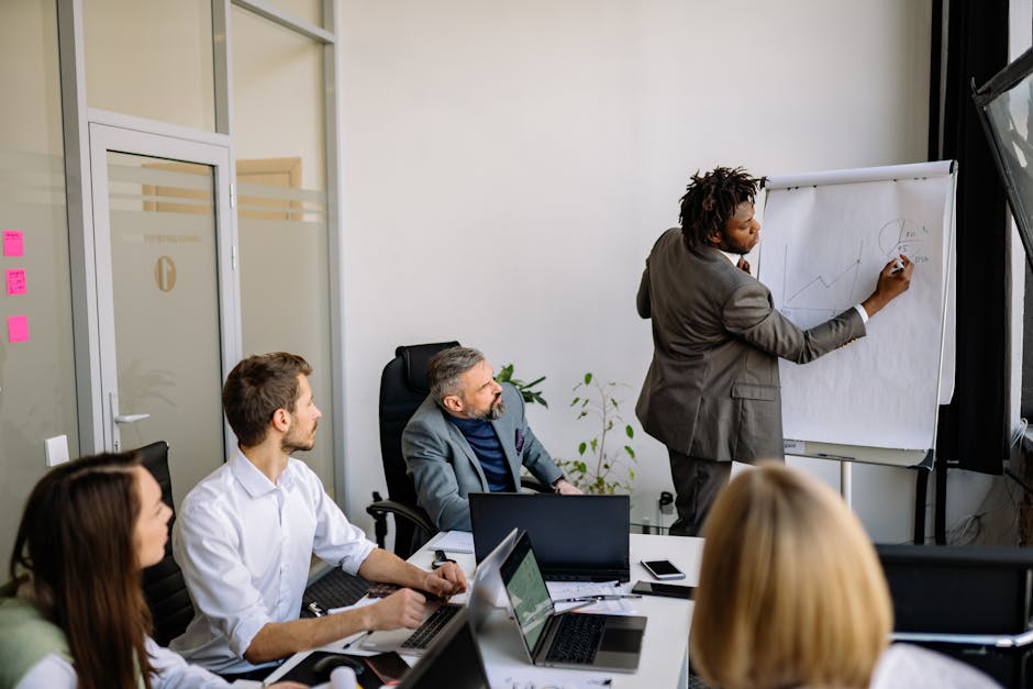 A diverse team in a modern office engaged in a strategic business meeting led by a presenter drawing on paper